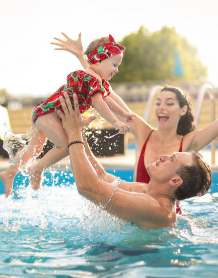 Un père jouant avec son enfant dans une piscine. 